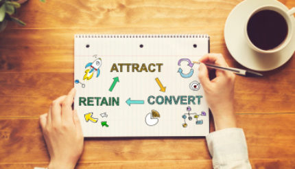 Attract Convert Retain text with a person holding a pen
